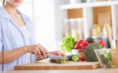 Young woman cutting vegetables in kitchen at home.