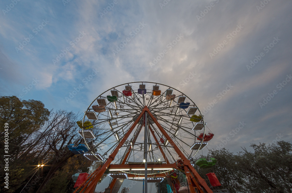 Ferris wheel bottom view in the early evening under blue sky at sunset Ferris wheel bottom view in the early evening under blue sky at sunset