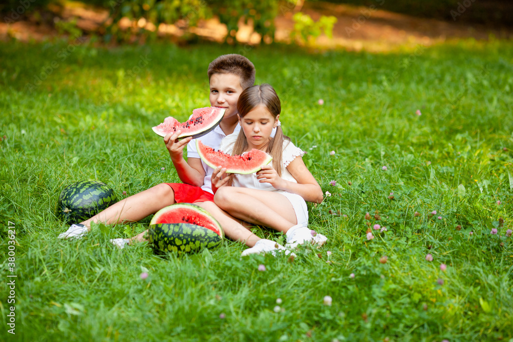 boy and girl sit on the grass and eat watermelon boy and girl sit on the grass and eat watermelon