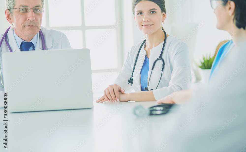Serious medical team using a laptop in a bright consulting room Serious medical team using a laptop in a bright consulting room