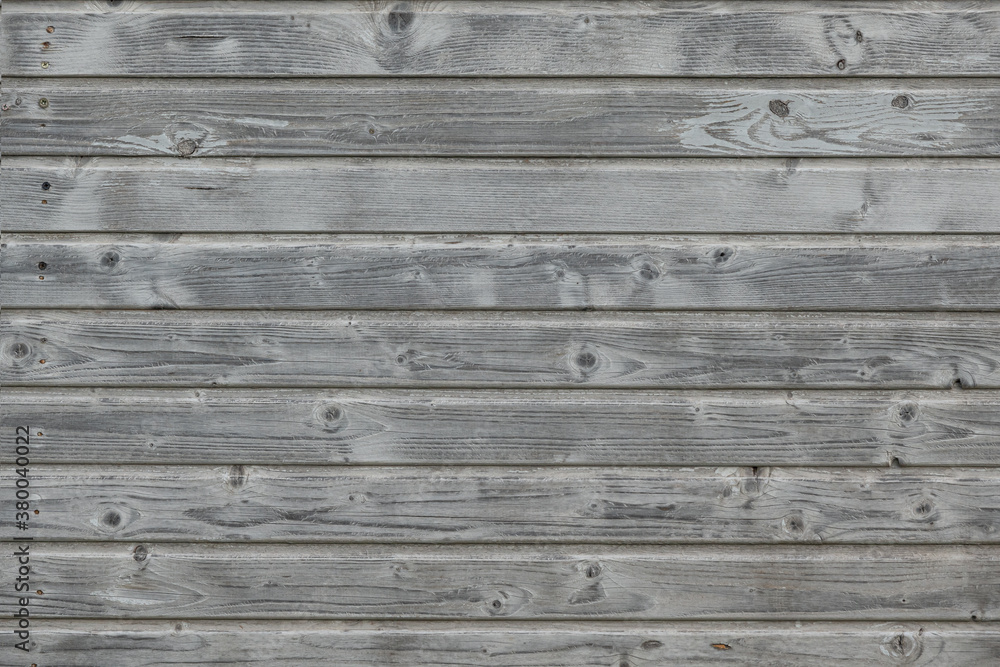 Gray wall of a wooden house. The wood texture is visible on the boards. Background.