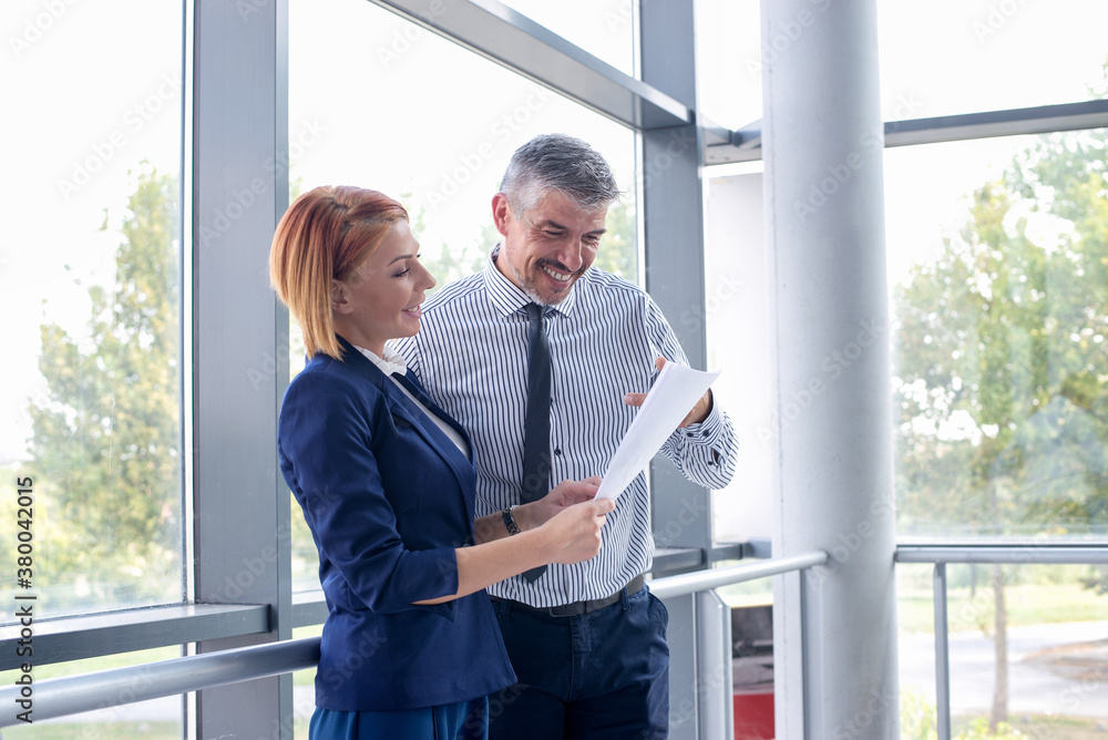 Two business people talking at office corridor Two business people talking at office corridor