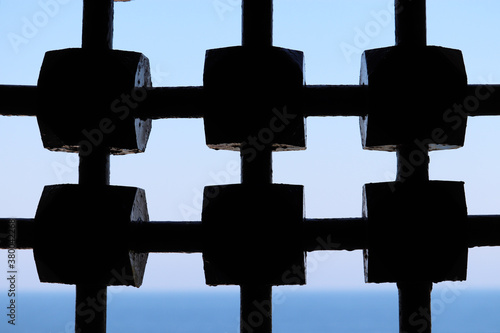 View through ancient metal lattice to sea and sky. Latticed window of medieval castle
