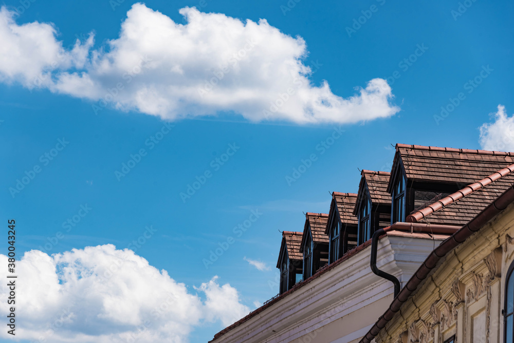 Haus mit Dachgauben vof b lauem Himmel mit Wolken Haus mit Dachgauben vof b lauem Himmel mit Wolken
