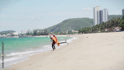 Acrobatic jump of a professional kitesurfer who jumps from the sea wave onto the beach sand on his kite, the athlete demonstrates a sports trick, jumping with a kite and board in the air to the ground