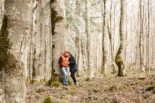 a couple, a man and a woman stand near a tree in a mountain forest in winter. honeymoon. walking and traveling.