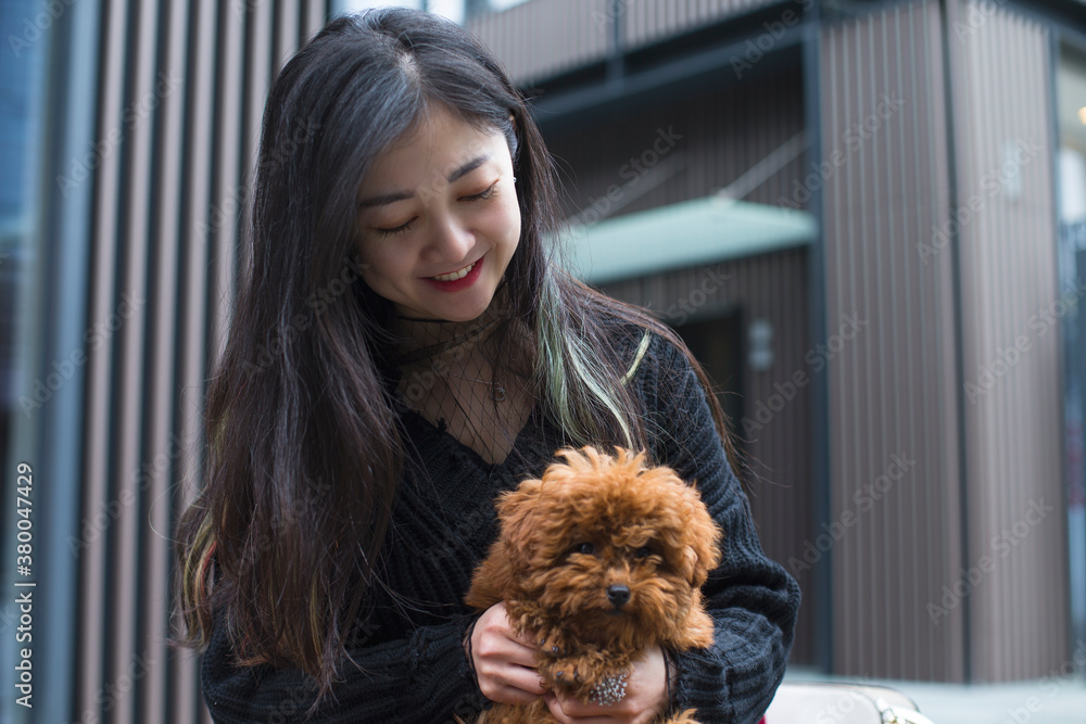 One happy asian woman holding her small dog outdoor One happy asian woman holding her small dog outdoor