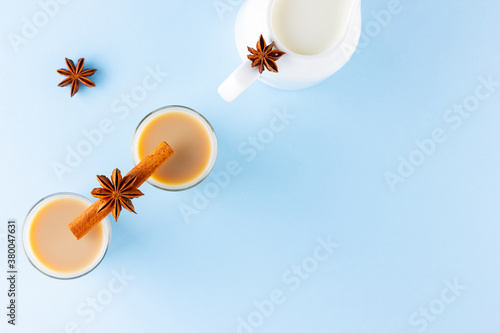 Tea with milk and spices on a blue background. Masala chai in turkish tea cups. Indian national drink and milk jug on a pastel background. Copy space. Top view