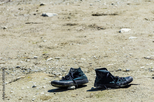 pair of old black dirty boots forgotten in empty field © olegmayorov