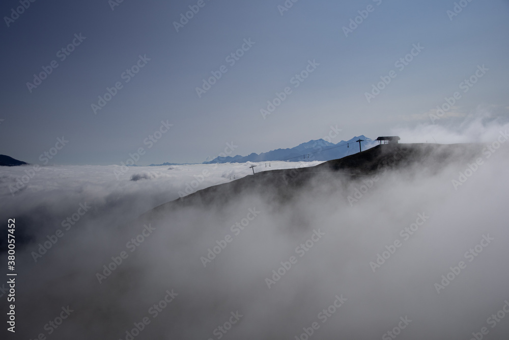 A ski lift above the clouds in the morning mist