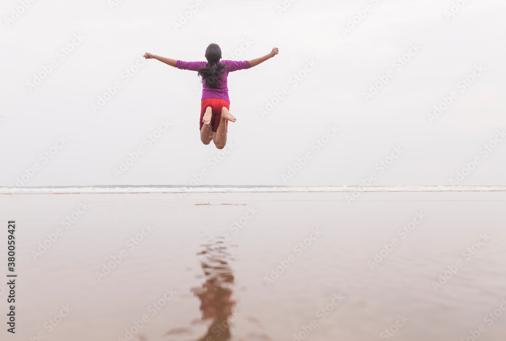 Teenage girl jumping in the air and making fun in a sea beach Teenage girl jumping in the air and making fun in a sea beach