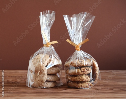 Oatmeal cookies with walnuts and raisins and almond cookies in a transparent bags on a wooden table. Closeup