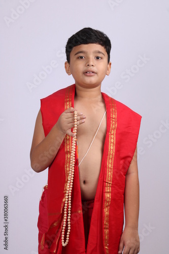Cute boy in Indian ethnic  wear chanting God's name / jaap. using rosary string of prayer beads or japamala photo