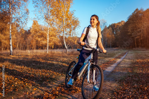 Riding bicycle in autumn forest. Young woman having rest after workout on bike enjoying nature. Healthy lifestyle