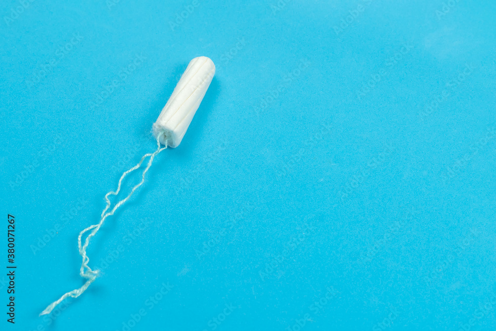 Medical female tampon on a blue background with copy space. Hygienic white tampon for women. Menstruation, a means of protection. Medical female tampon on a blue background with copy space. Hygienic white tampon for women. Menstruation, a means of protection.