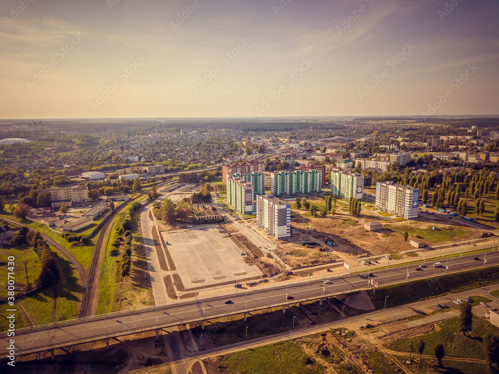 Part of the city with new buildings, bridge, construction site on a summer day at sunset, view from the drone.
