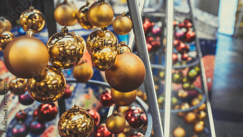 Close up of christmas toys suspended on metal construction in hall in shopping center. Yellow christmas balls hanging on strings for room decoration and create festive mood.