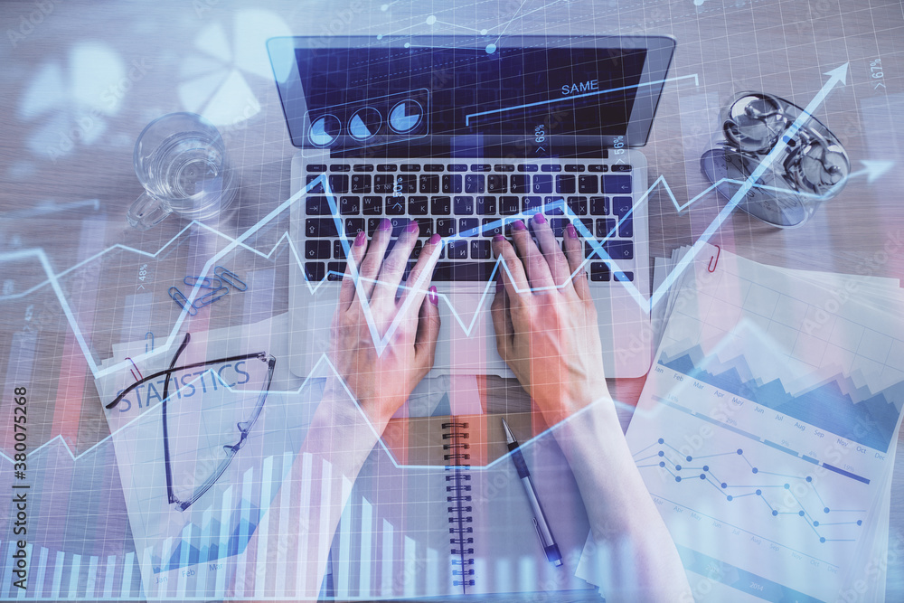 Double exposure of woman hands working on computer and forex graph hologram drawing. Top View. Financial analysis concept.