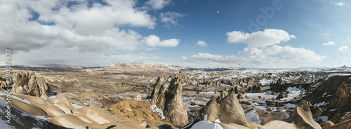 panoramashot of snowcovered mountain landscape of cappadocia with rising hot air balloons, turkey photo