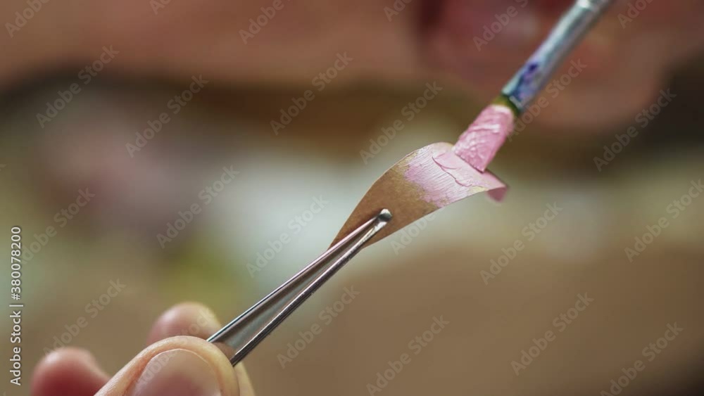 Man uses brush to put oil paint pink color on small piece of paper Man uses brush to put oil paint pink color on small piece of paper