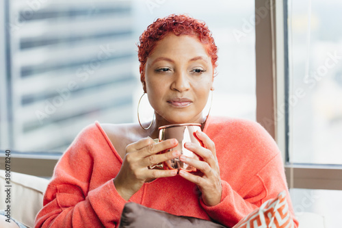 Black woman relaxing and drinking tea at home on couch photo