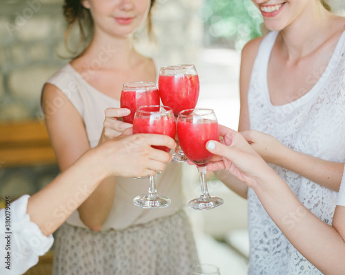 Cheerful women clanging juice glasses photo