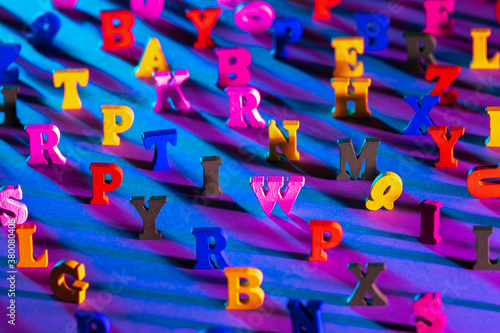 Multi-colored letters stand on a blue background. Small letters are randomly placed. Focusing on central characters. Concept - abc blocks. Alphabet as a symbol of study of letters. Learning ABC.
