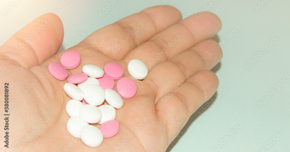 Open palm of a woman with a bunch of white and pink pills, health and medicine concept, close-up Open palm of a woman with a bunch of white and pink pills, health and medicine concept, close-up