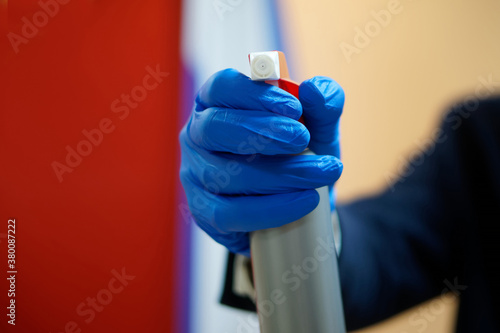 A man in a business suit and blue protective gloves holds a spray bottle with a disinfectant solution. Pandemic and covid protection. Office report.