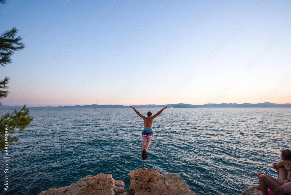 Man jumping in the sea from a cliff Man jumping in the sea from a cliff