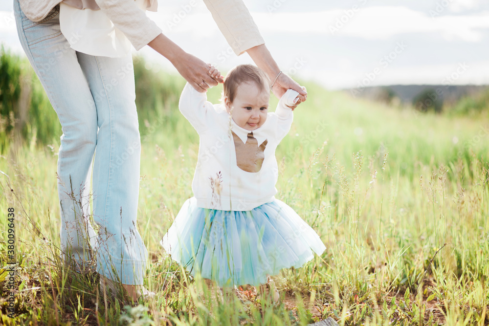 Young woman teaching her toddler daughter to walk Young woman teaching her toddler daughter to walk