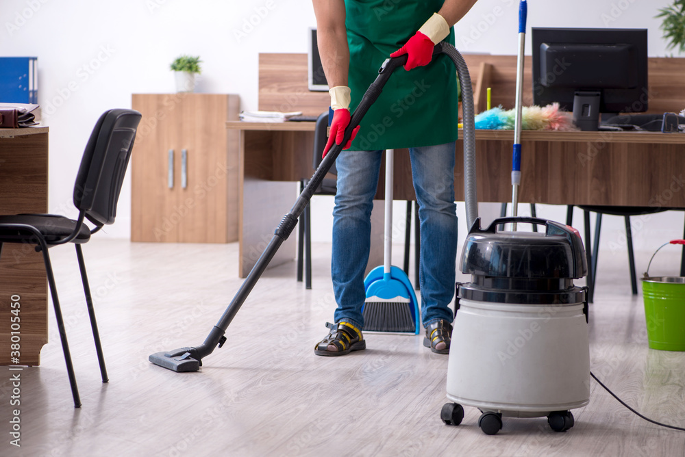 Young male contractor cleaning the office