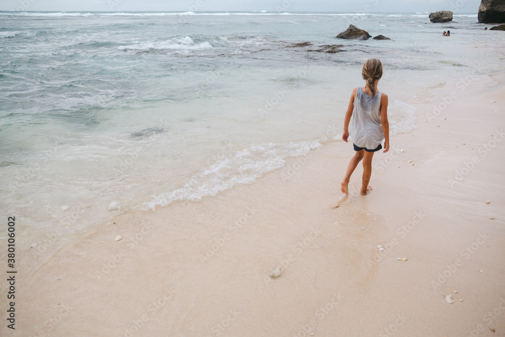 Young girl walking on sandy beach on cloudy day Young girl walking on sandy beach on cloudy day