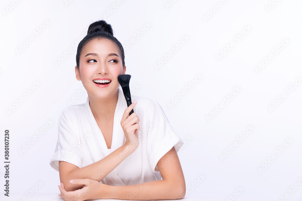 Glamour young woman smile and holding make-u brush with healthy clean and fresh skin while looking at camera over isolated white background. Beauty and cosmetics concept. Glamour young woman smile and holding make-u brush with healthy clean and fresh skin while looking at camera over isolated white background. Beauty and cosmetics concept.
