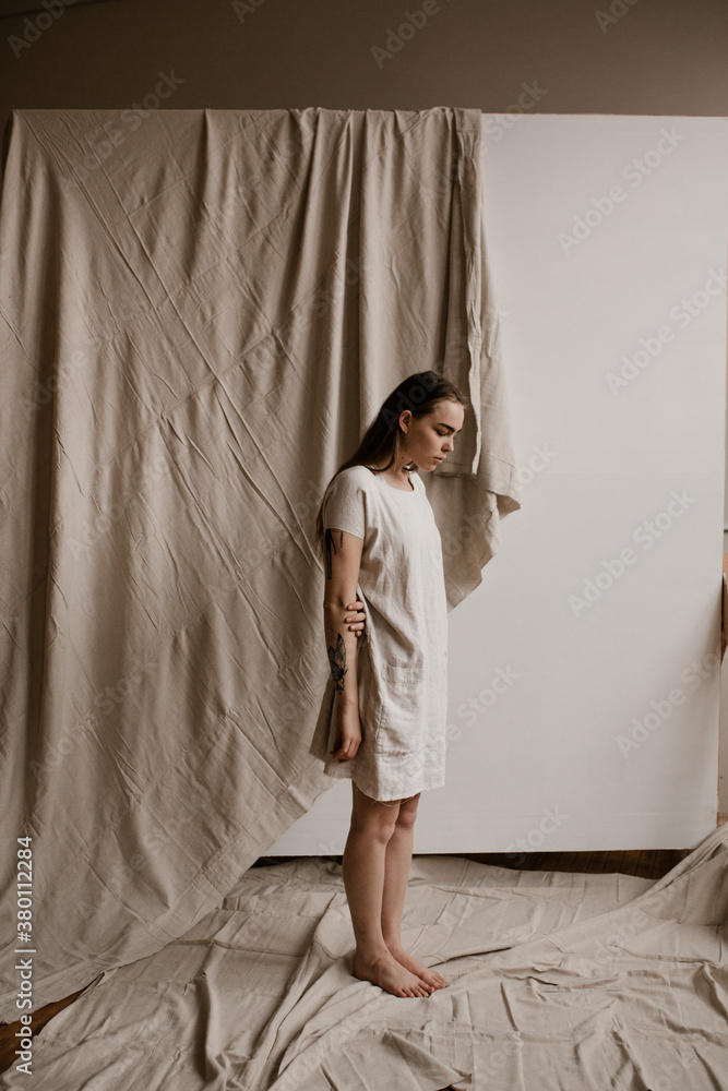young woman standing in front of wrinkled cloth wearing simple cloth dress young woman standing in front of wrinkled cloth wearing simple cloth dress