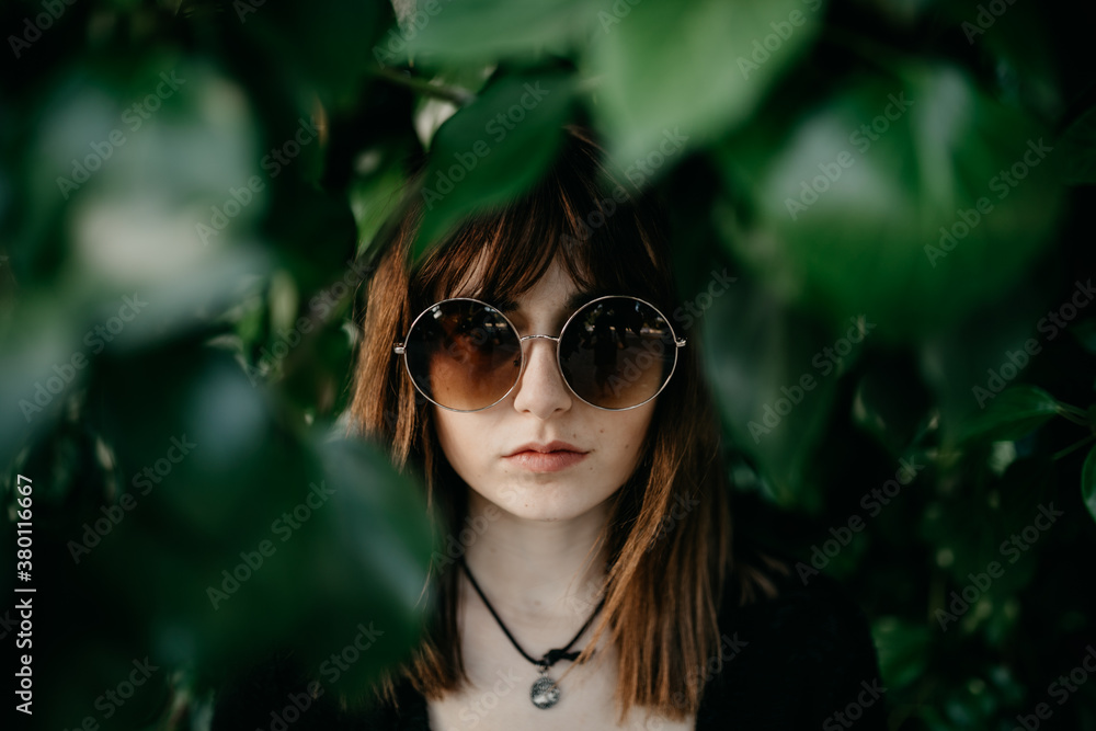 Serious Young Woman in Front of and Framed by Leaves on a Tree Serious Young Woman in Front of and Framed by Leaves on a Tree