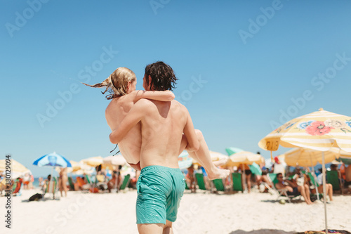 Young man carries woman on beach