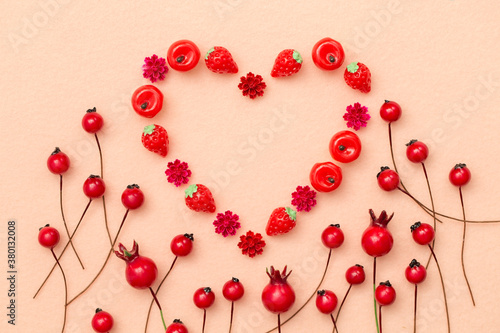 Miniature decorative fruits and red berries arranged in a heart shape on felt fabric