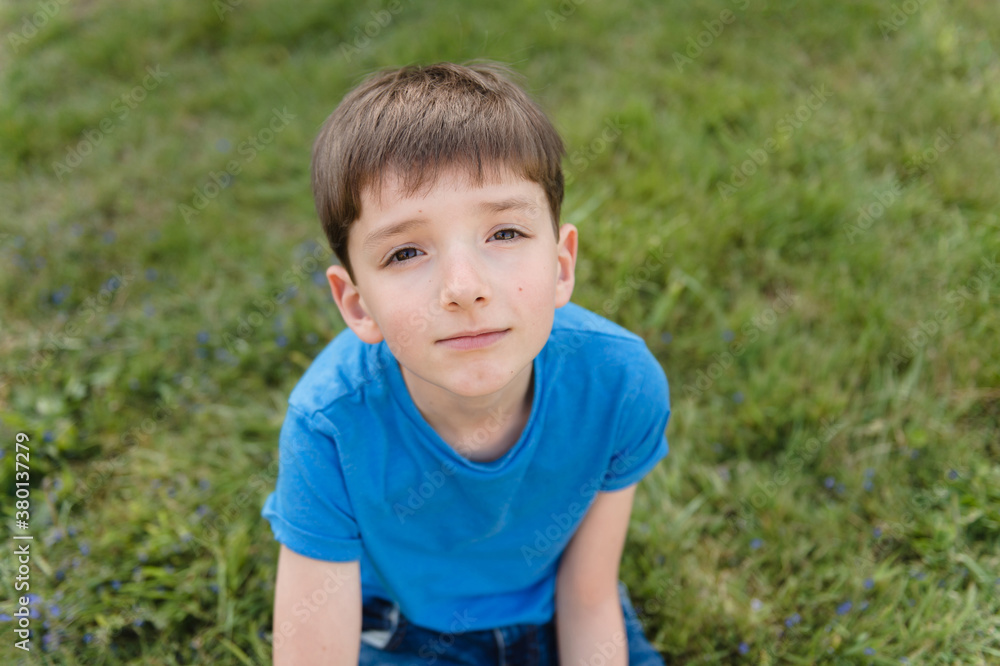 Adorable tween boy resting on a lawn covered with blue flowers Adorable tween boy resting on a lawn covered with blue flowers