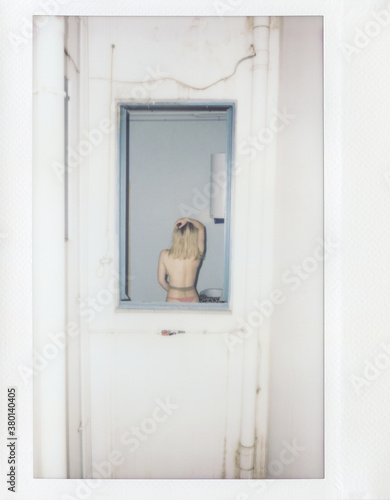 Topless woman in tights through window frame.
