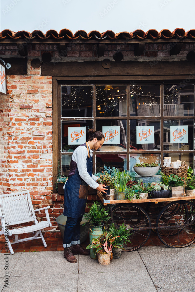 Small artisan business owner arranging plants in front of store Small artisan business owner arranging plants in front of store