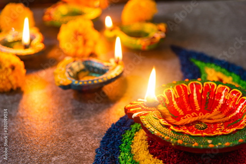 Close up clay lit light a fire already on Diya or oil lamp with flowers on concrete background, Decoration of Hinduism rangoli, Happy celebration Deepavali, or Diwali Indian festival concept