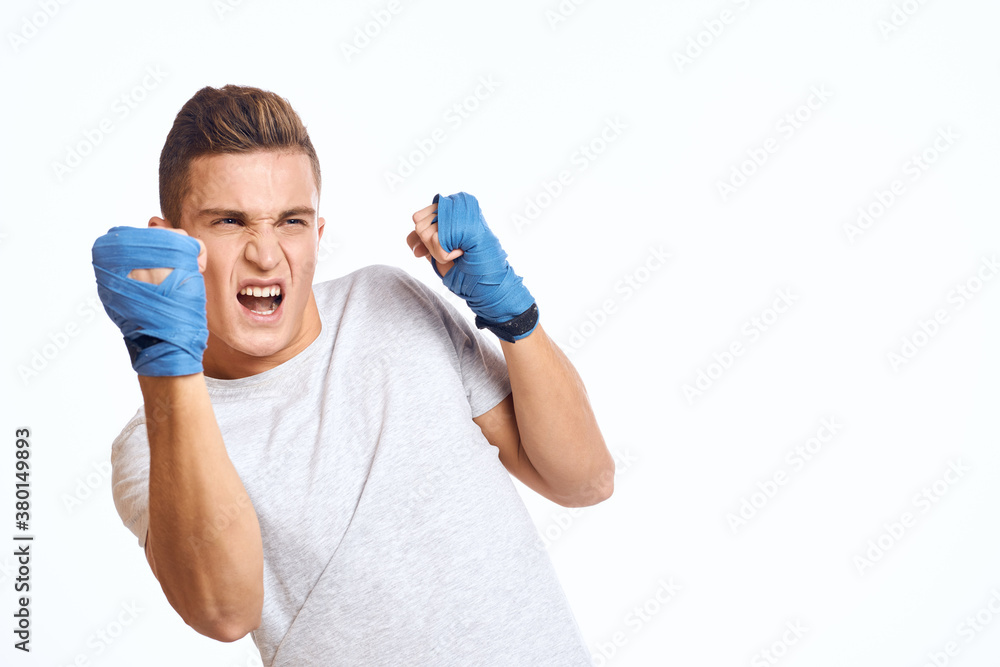 sporty male boxer in blue gloves practicing punches on a light background cropped view sporty male boxer in blue gloves practicing punches on a light background cropped view