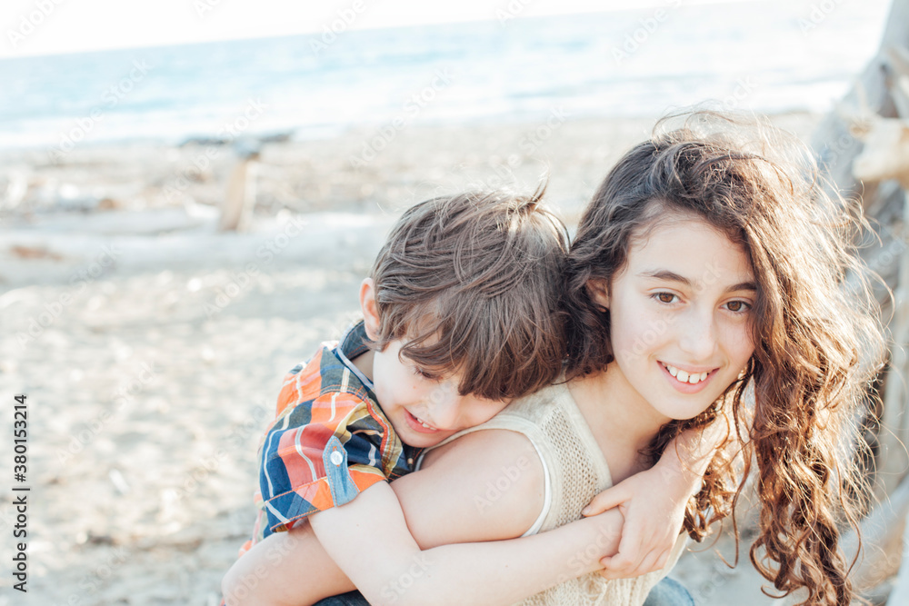 Sister carrying her brother on the Beach at Sunset Sister carrying her brother on the Beach at Sunset