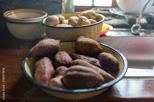 Bowls of sweet and yellow potatoes on a rustic kitchen bench photo