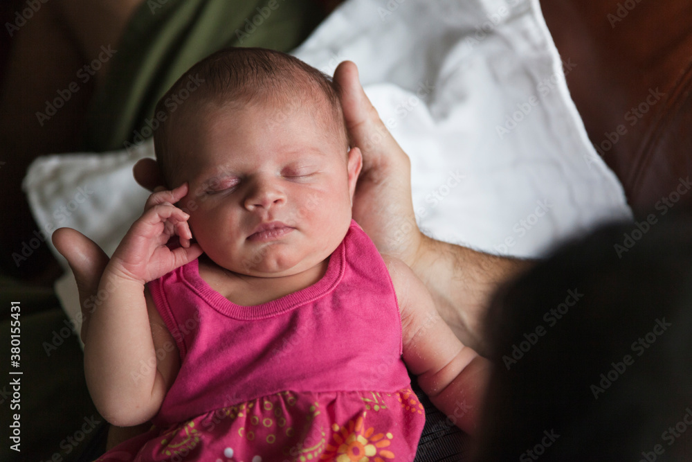 An infant girl is held in her father's hands. An infant girl is held in her father's hands.