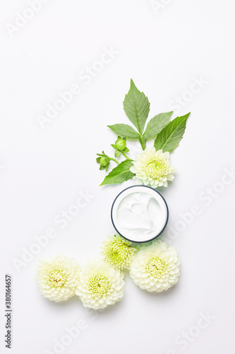 spa concept or template. florals compositions made white dahlia flowers and skincare cream. vertical frame, top view concept