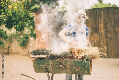 Young man putting straw on fire. photo