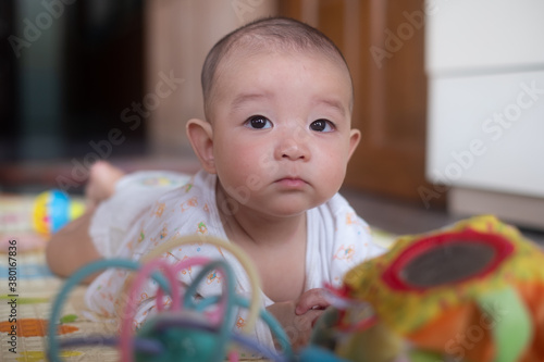 Photography Curious Asian infant baby boy lie on the stomach or prone playing toy
