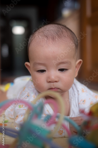 Curious Asian infant baby boy lie on the stomach or prone playing and looking at toy